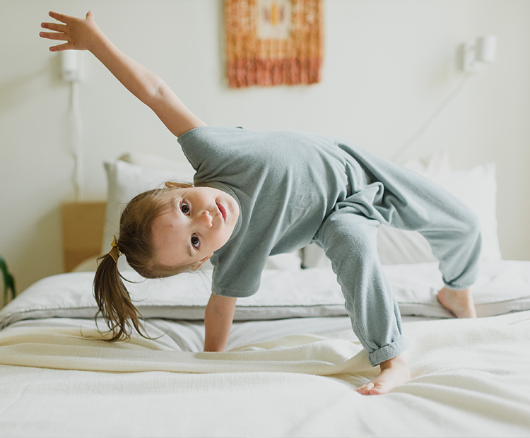 young girl doing yoga on bed
